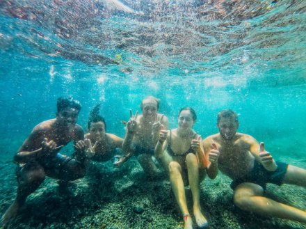 A group of five, underwater in the clear blue sea, while snorkeling in Gili Trawangan, Bali, Indonesia 
