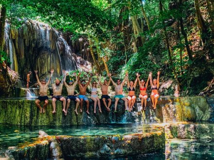 A group sitting at the edge of the serene waterfall on Mojo Island, Indonesia