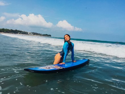 A girl in the sea with her surfboard on Kuta beach Bali Indonesia 