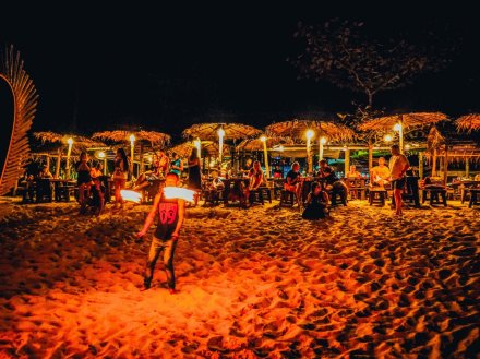Fireshow on bottle beach in Thailand and people having drinks at tables in the background