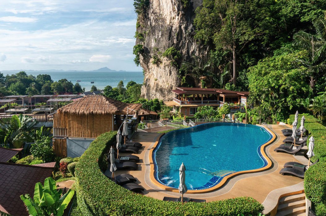 A photo of a hotel in Railay beach, Krabi, Thailand showing the blue pool, sun loungers and the surrounding lush greenery