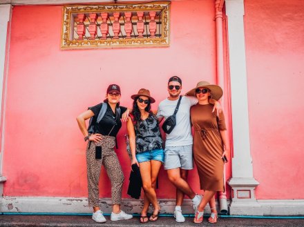 A group of four posing in front of a bright pink wall in Phuket, Thailand 